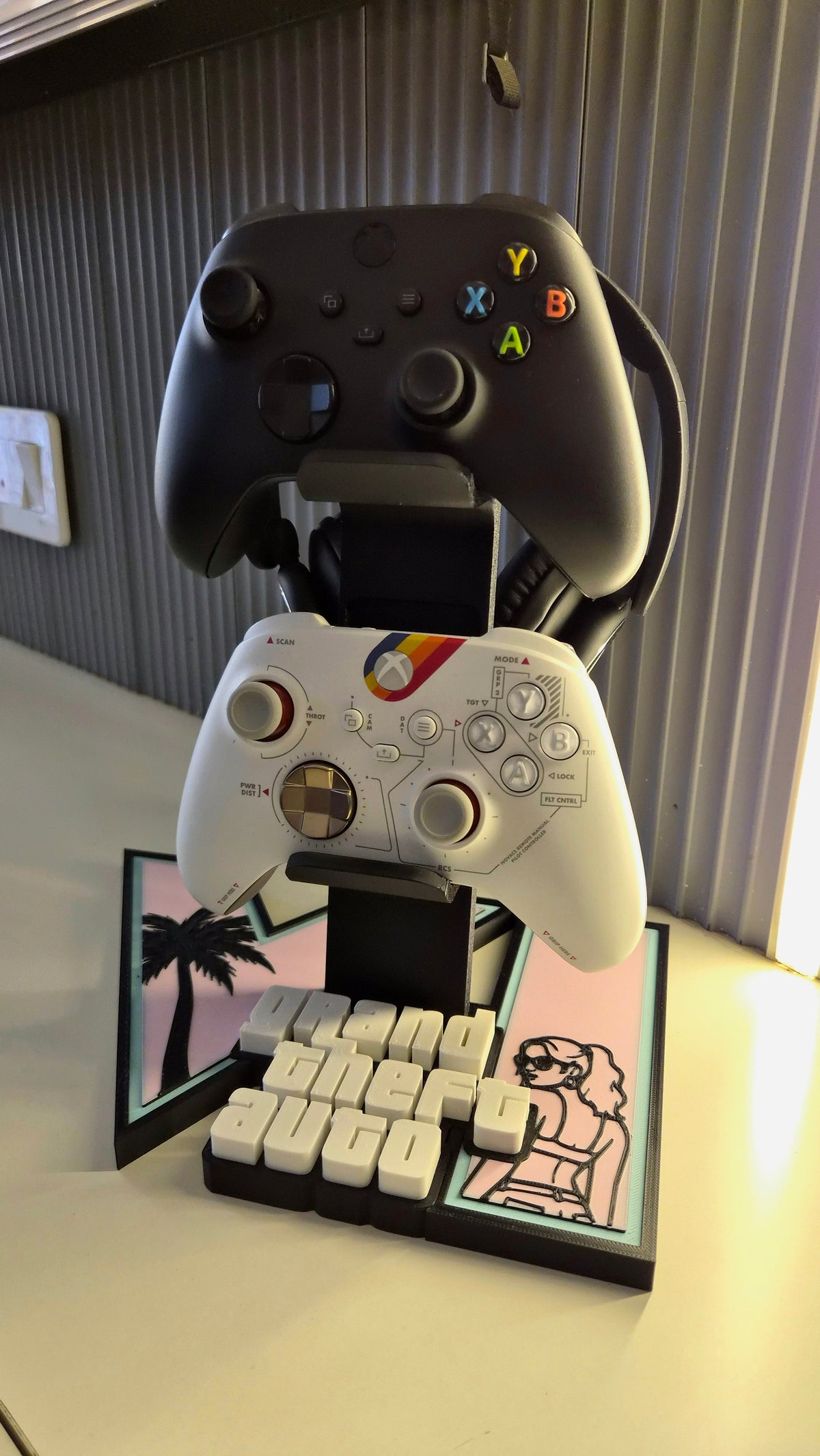 Close-up of the GTA 6 stand showing controller supports, headset storage and raised Grand Theft Auto lettering